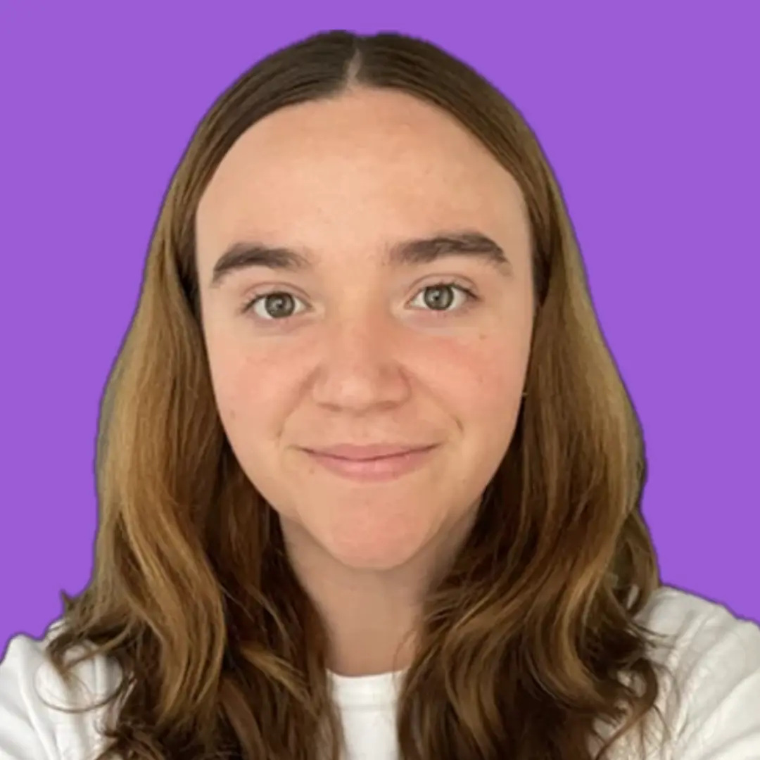 A photo of Manu Salcedo, who is wearing a white t shirt and smiling against a purple background