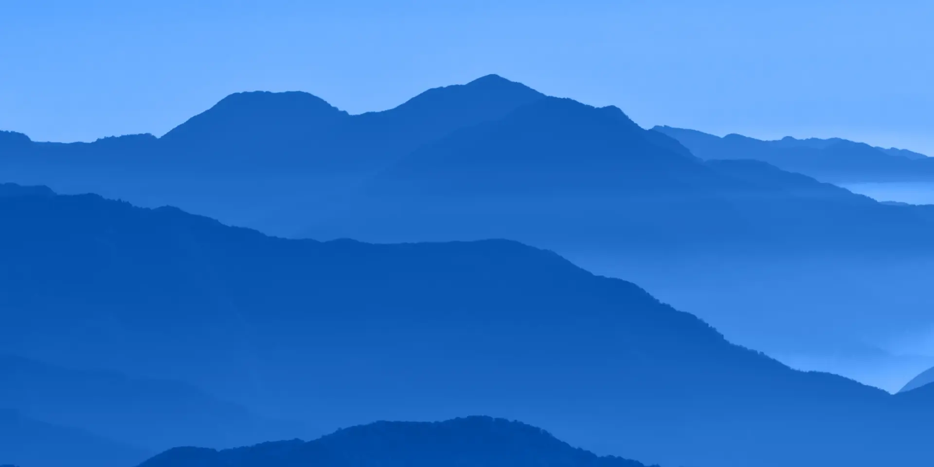 Monochromatic blue photograph of mountains receding away from the camera.