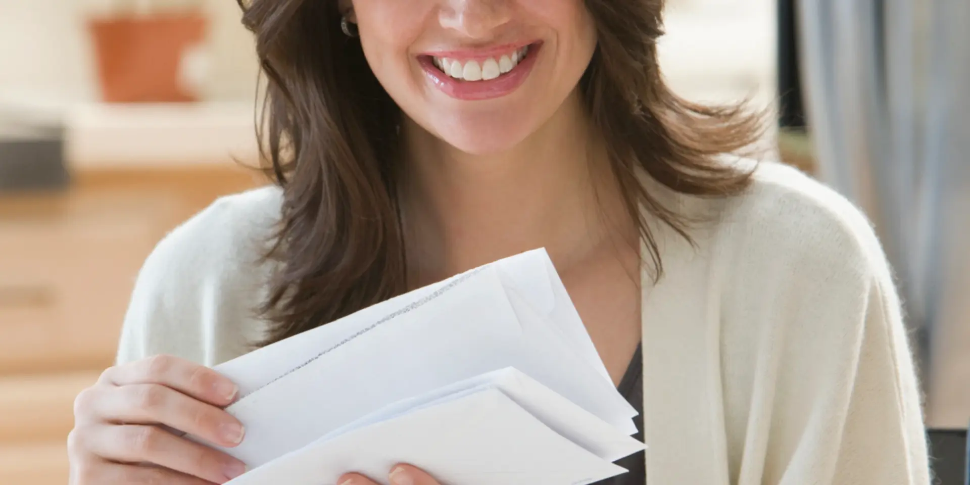 Woman smiling and holding a stack of envelopes.