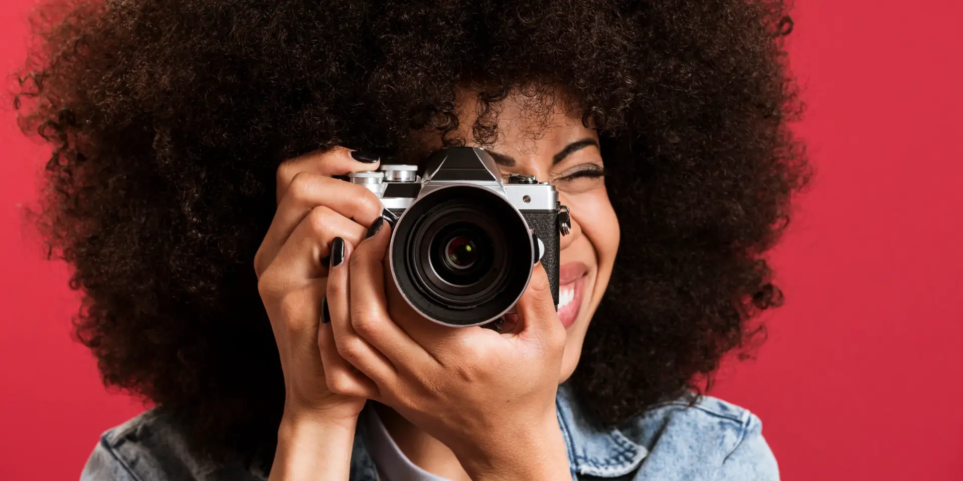 A female photographer holding a camera and smiling.