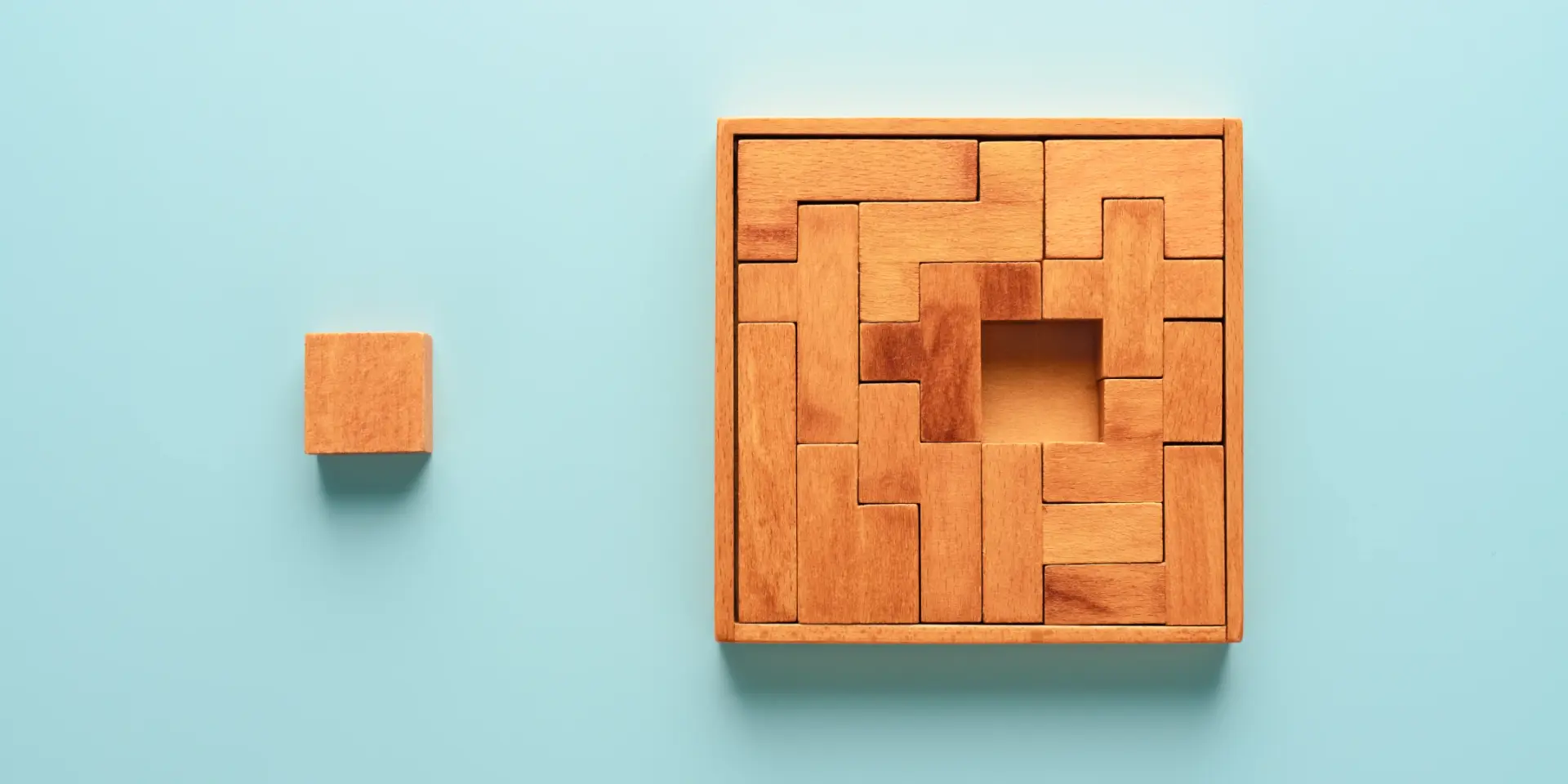 an image of a wooden building block puzzle with one piece outside of the puzzle
