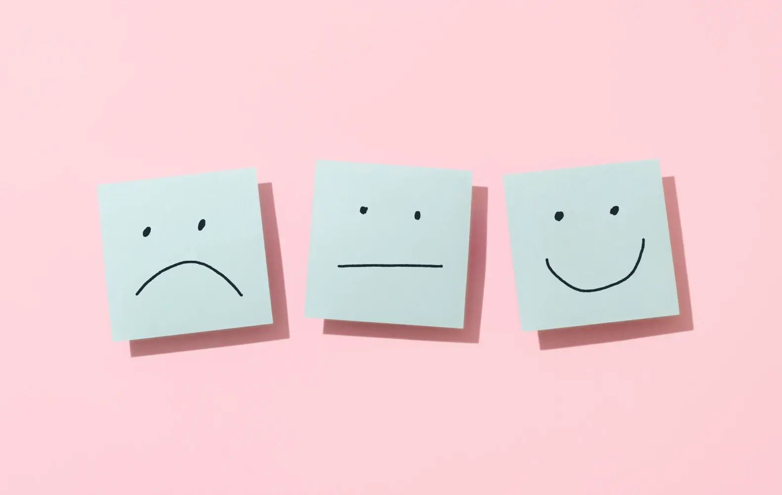 Three sticky notes with faces on them to indicate sad, neutral, and happy emotions.