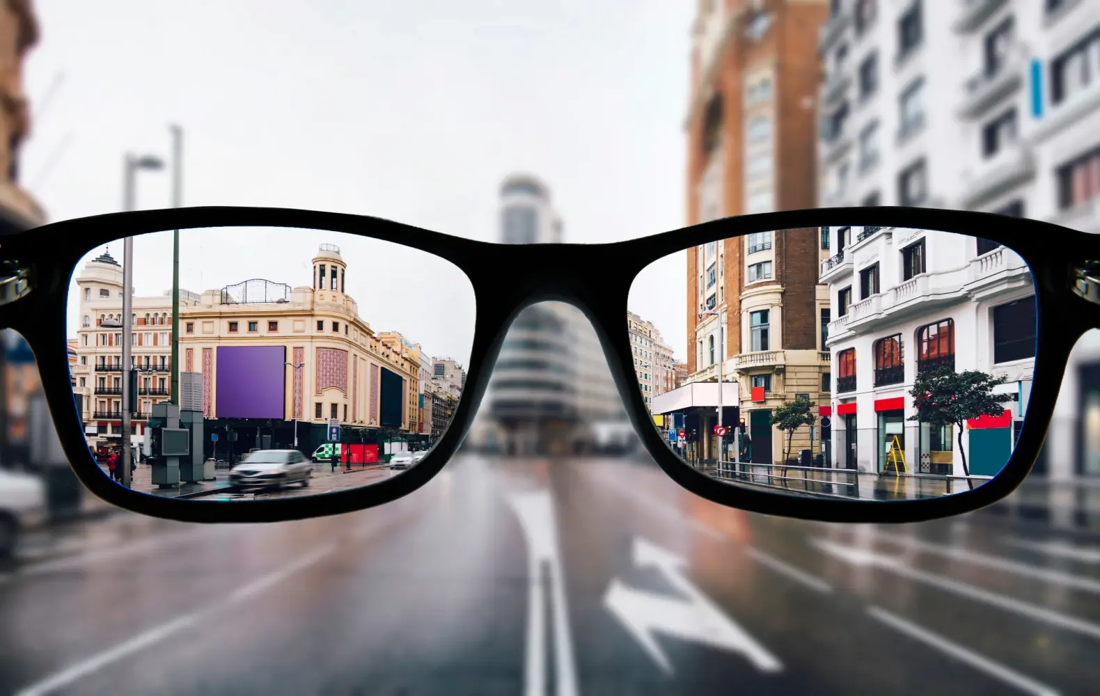 A city viewed through a pair of glasses: The city is blurry outside the frames of the glasses and clear within the frames. 